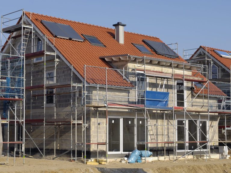 Sanierung eines Zweifamilienhauses: Dach- und Fassadensanierung im Gange, ein Gerüst steht bereit.